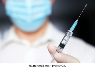 Seringue dans la main du médecin, homme dans le masque médical et gants de protection se préparant à l'injection. Concept de vaccination pendant la pandémie du virus 19