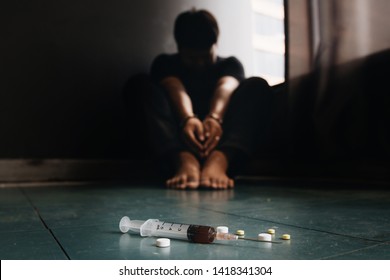 Syringe And Drugs With Out Of Focus Man Sitting On Floor And Hands Locked In Handcuffs.drug Addicted.International Day Against Drug Abuse And Illicit Trafficking