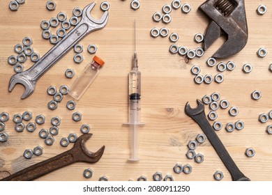 Syringe Filled With Liquid, A Bottle Of Vaccine Lies On Table Among A Variety Of Wrenches And Metal Nuts. Vaccine Production Concept. 