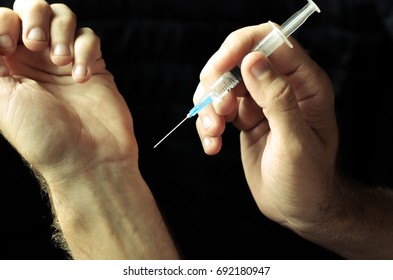 Syringe in hand - Shutterstock ID 692180947