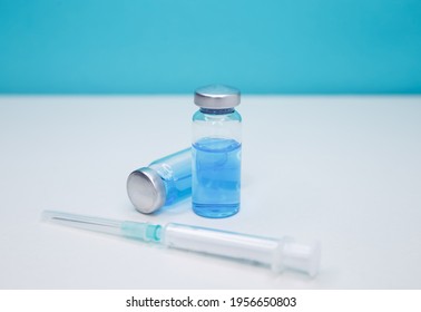 A syringe is injected into a vial. Coronavirus vaccination and immunization concept. Plastic medical syringe and vial vaccine. Monochromatic image of glass vials and a syringe. Fight pandemic.