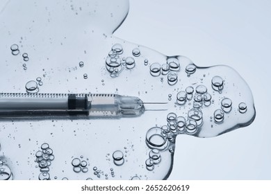 A syringe for injection in an appetizing drop with bubbles. Blue steel background.