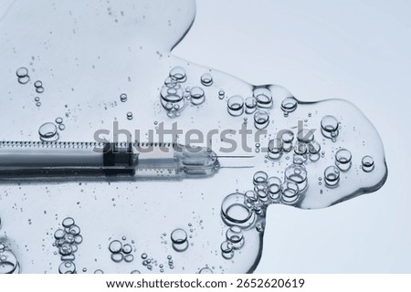 A syringe for injection in an appetizing drop with bubbles. Blue steel background.