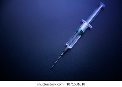 A syringe with an injection solution on dark background with copy space. Syringe with vaccination. Liquid medication or drug.