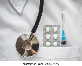 Syringe And Injection Vial Lying In The Pocket Of A Doctor's Gown. Close-up, Indoors, No People. Daylight, Studio Photo. Healthcare Concept