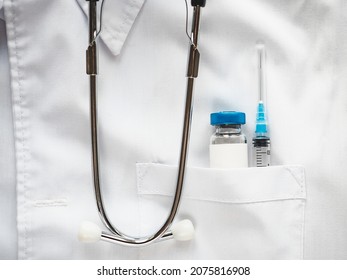 Syringe And Injection Vial Lying In The Pocket Of A Doctor's Gown. Close-up, Indoors, No People. Daylight, Studio Photo. Healthcare Concept