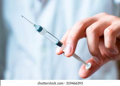 Syringe, medical injection in hand, palm or fingers. Medicine plastic vaccination equipment with needle. Nurse or doctor. Liquid drug or narcotic. Health care in hospital. - Powered by Shutterstock