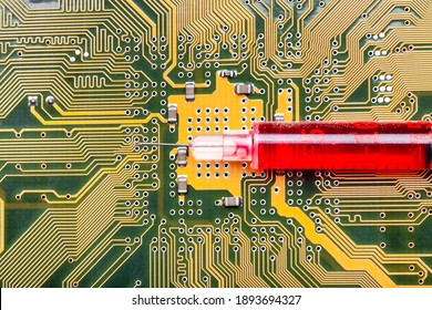syringe with needle filled red medicinal product lies on silicone printed circuit board with contact tracks of electronic equipment of modern medicine vaccine cyber implantation treatment.