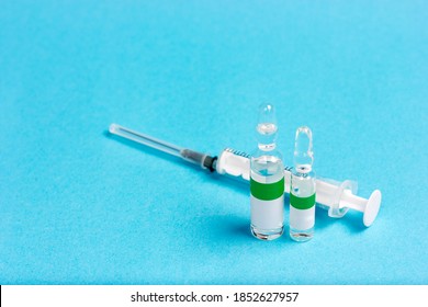 Syringe And Three Ampoules On A Blue Background. Antivenom In Ampoules. Coronavirus Vaccine.