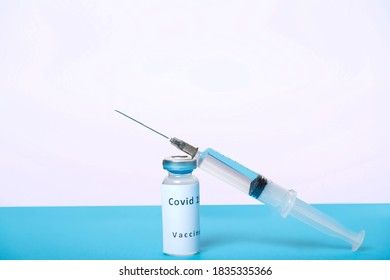 A syringe and a vial with a virus vaccine are on a blue table, top view.