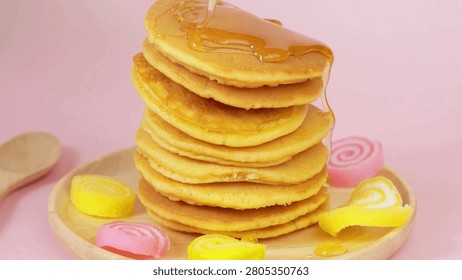 syrup being poured onto stack of steaming pancakes on pink background. Homemade Pancake for morning breakfast. Maple syrup being poured over pancakes.
