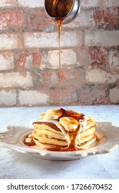 The syrup flows out onto a stack of pancakes. Dish on a white plate. Copy space. Side view
