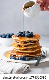 Syrup pouring on pancakes. Pancakes with blueberries and sweet syrup