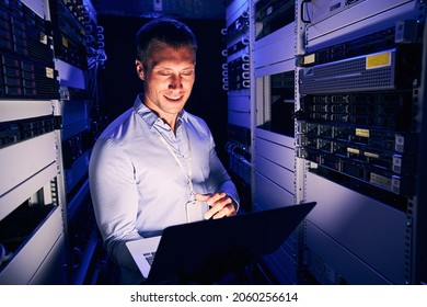 Sysadmin Working On Notebook Computer In Server Room