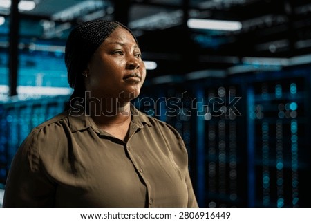 System admin walking in computing facility with server hardware supporting business needs, while doing checkup, ensuring equipment works at optimum operational performance for smooth operations.