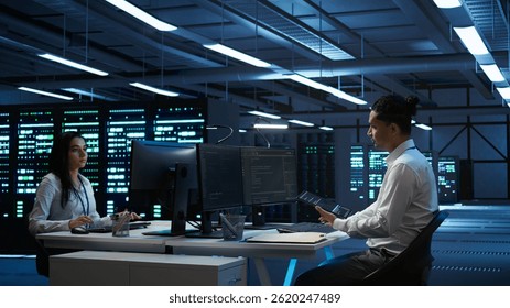 System administrator in data center installing software on computer, troubleshooting issues using tablet. IT staff member in server hub establishing performance benchmarks, camera B