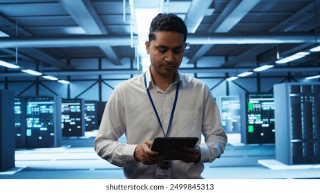 System administrator in data center managing and maintaining databases, ensuring data integrity, security and availability. IT worker updating server room supercomputers systems, camera B
