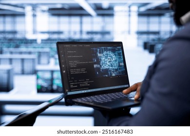 System administrator in data center using laptop to visualize artificial intelligence neural networks made up of interconnected nodes. Close up of employee oversees AI systems processing information