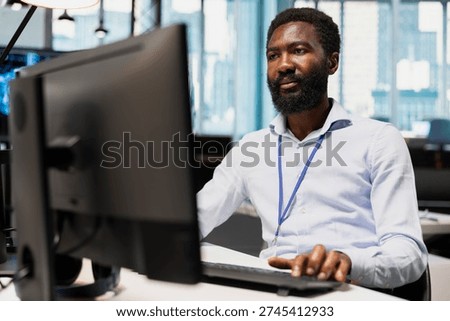 System administrator designing and developing software applications, optimizing code for performance and scalability. African american man in office using PC to resolve bottlenecks
