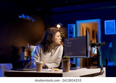 System administrator doing software debugging on PC at home, checking broken lines of code displayed on monitors. Proficient IT specialist in apartment fixing coding problems, typing on keyboard