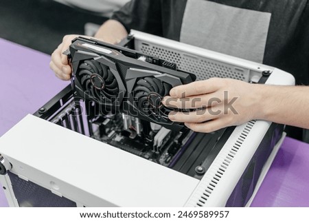 system administrator installing graphics card into system unit, assembling PC of different accessories or components, close-up view of hands, computer repair and maintenance concept