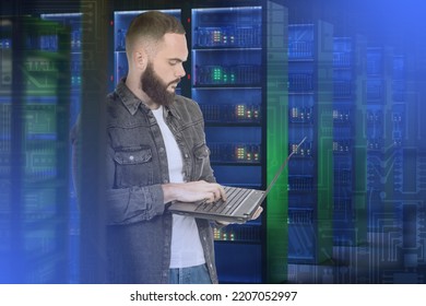 System Administrator. Man In Server Room. Guy Is Typing In Laptop. Man Among Server Racks. System Administrator Configures Internet Equipment. Career In IT Industry. Portrait System Administrator