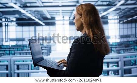 System administrator in server hub checking recovery plan on laptop, monitoring energy consumption. IT expert uses notebook in data center workspace, ensuring rigs are functioning optimally, camera B
