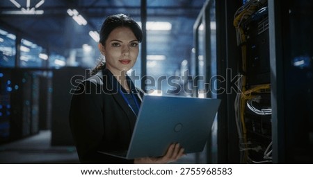System administrator uses a laptop in data center. Portrait looking in camera. Server racks in server room. Software diagnostics, technical service support for infrastructure