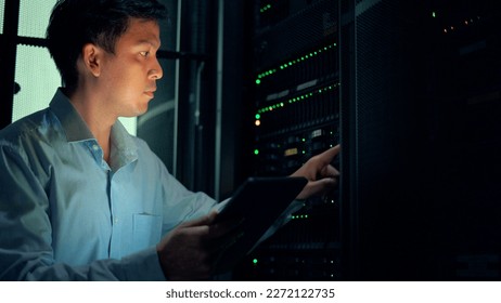 System administrator using digital tablet while working in data center.