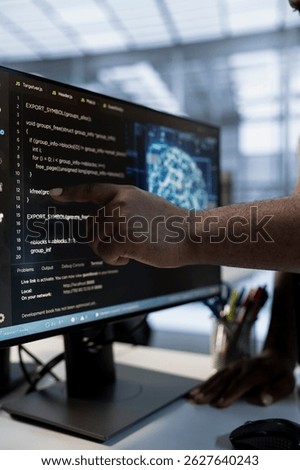 System administrator using machine learning applications to optimize server farm operations. IT expert pointing to PC monitor, implementing server virtualization in data center facility