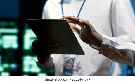 System administrator using tablet to check high tech facility security features protecting against unauthorized access, data breaches, phishing attacks and other cybersecurity threats, close up
