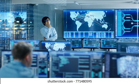 In the System Control Room Chief Engineer Thinks While Standing Before Big Screen with Interactive Map on it. Data Center is Full of Monitors Showing Graphics. - Shutterstock ID 771480595
