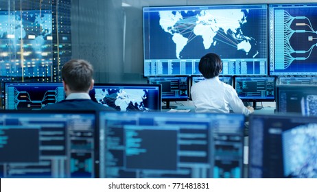 In the System Control Room Operator and Administrator Sitting at Their Workstations with Multiple Displays Showing Graphics and Logistics Information. - Powered by Shutterstock - Get 15% off with code: PIKWIZARD15