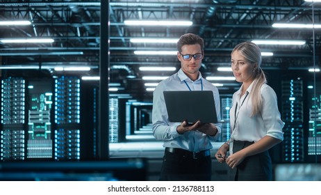 In the System Control Room Project Manager and IT Technical Engineer with Laptop Have Discussion, Gesturing and Looking Away. Team of Two Professionals Finding IT Problem Solution - Powered by Shutterstock