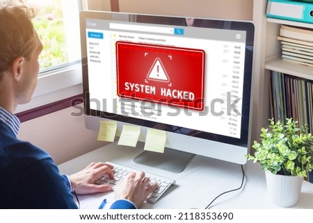 System hacked alert on computer screen after cyber attack on network. Cybersecurity vulnerability on internet, virus, data breach, malicious connection. Employee working in office.