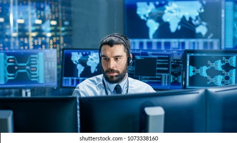 In The System Monitoring Room Dispatcher Wearing Headset Observers Proper Functioning Of The Facility. He's Surrounded By Screen Showing Technical Data.
