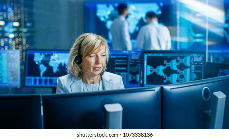 System Monitoring Room Female Dispatcher Control Correct Functioning Of The System. In The Background People Working With Interactive Map.