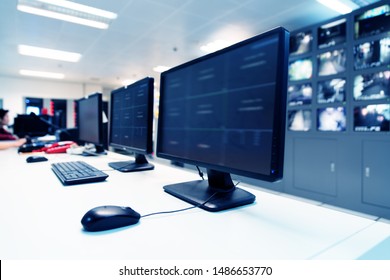 System Security Specialist Working At System Control Center. Room Is Full Of Screens Displaying Various Information.