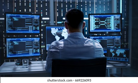 System Security Specialist Working at System Control Center. Room is Full of Screens Displaying Various Information. - Shutterstock ID 669226093