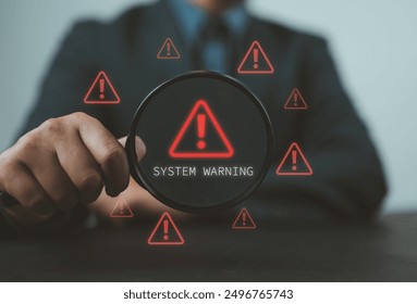 System Warning Alert, Cyber Security Concept. Hand holds magnifying glass over digital warning sign with red exclamation marks, system warning or potential malicious cyber attack alert. Cybersecurity, - Powered by Shutterstock