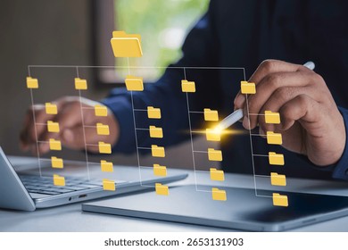 Systematic data storage for ease of use. Folder hierarchy structure and document management system DMS. Businessman using laptop computer and tablet for saving and classifying files.