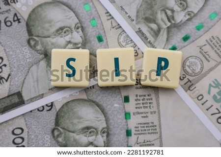 Systematic Investment Plan or SIP in mutual funds, denoted by the words SIP written on tiles on backdrop of Indian Rupee notes.