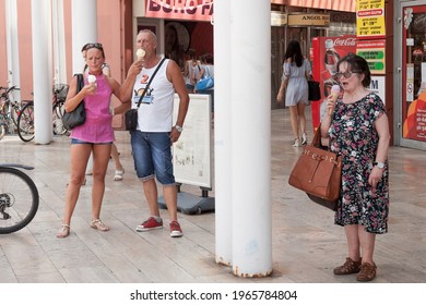 SZEGED, HUNGARY - JULY 21, 2018: Three People, A Couple Of Lovers And A Senior Old Woman Eating Ice Cream In Summer Near A Gelato Parlor In The City Center Of Szeged.