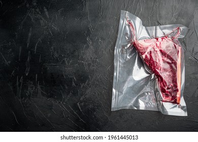 T Bone Or Florentine Dry Aged Steak In Vacuum Pack Set, On Black Stone Background, Top View Flat Lay, With Copy Space For Text