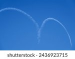 A T-50 Black Eagles is flying downward in blue sky with white smoke of heart shape for air show at Air Force Seongnam Base near Seongnam-si, South Korea

