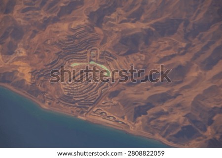 Taba Heights resort complex with turquoise lagoons built into the rugged desert mountains along the Red Sea coast as seen from a high altitude commercial airplane window, Taba, Egypt, Africa