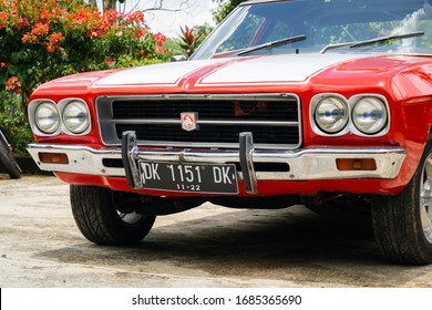 Tabanan, Bali / Indonesia - 29 February 2020: A Classic Red Muscle Car With Double White Strips, Named Holden Kingswood. Close Up View.