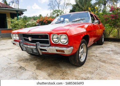 Tabanan, Bali / Indonesia - 29 February 2020: A Classic Red Muscle Car With Double White Strips, Named Holden Kingswood. Front Corner View.