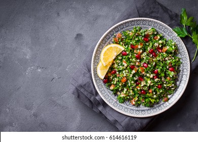 Tabbouleh salad, plate, rustic concrete background. Traditional middle eastern or arab dish. Levantine vegetarian salad with parsley, mint, bulgur, tomato. Part of middle eastern meze. Space for text - Shutterstock ID 614616119