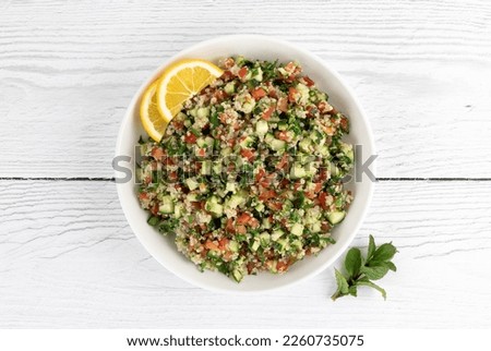 Tabbouleh salad with quinoa, tomatoes, cucumbers, parsley, mint and lemon juice on a white background. Top view. Healthy vegetarian salad.